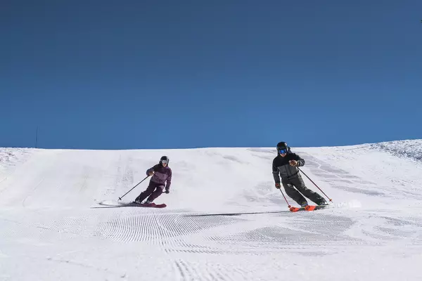 man and woman skiing down a slope