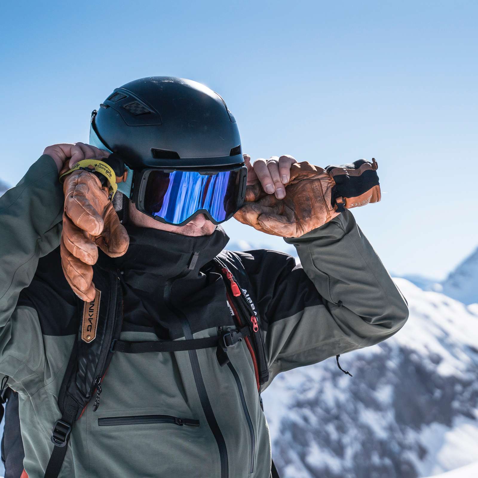 Man with ski helmet and goggles on with mountains behind
