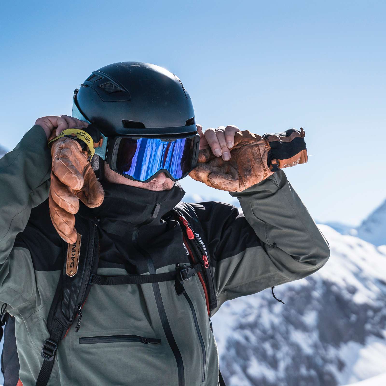 Homme avec casque de ski et lunettes avec montagnes derrière