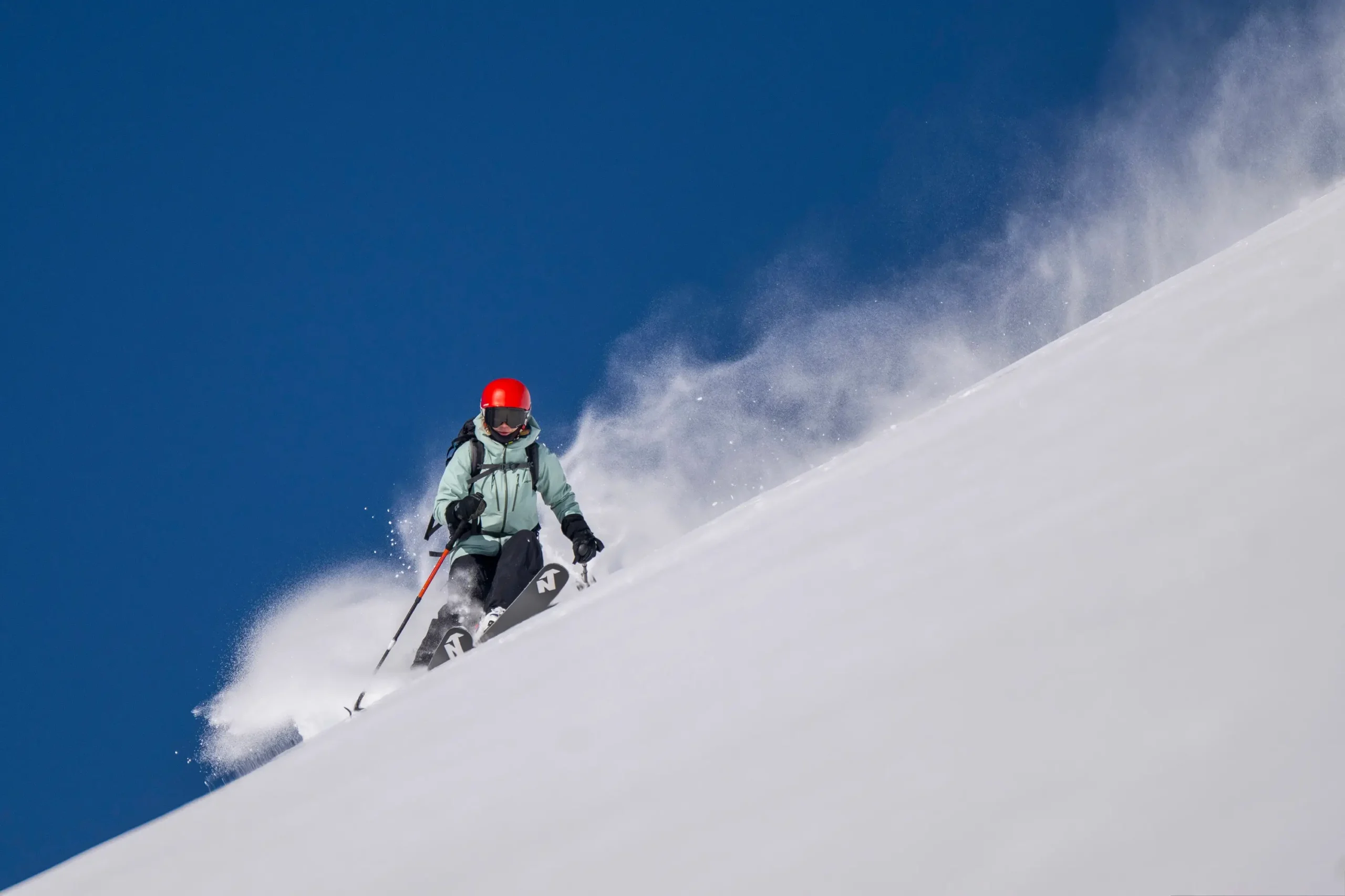 Un skieur faisant un virage dans la poudreuse avec un ciel bleu en arrière-plan