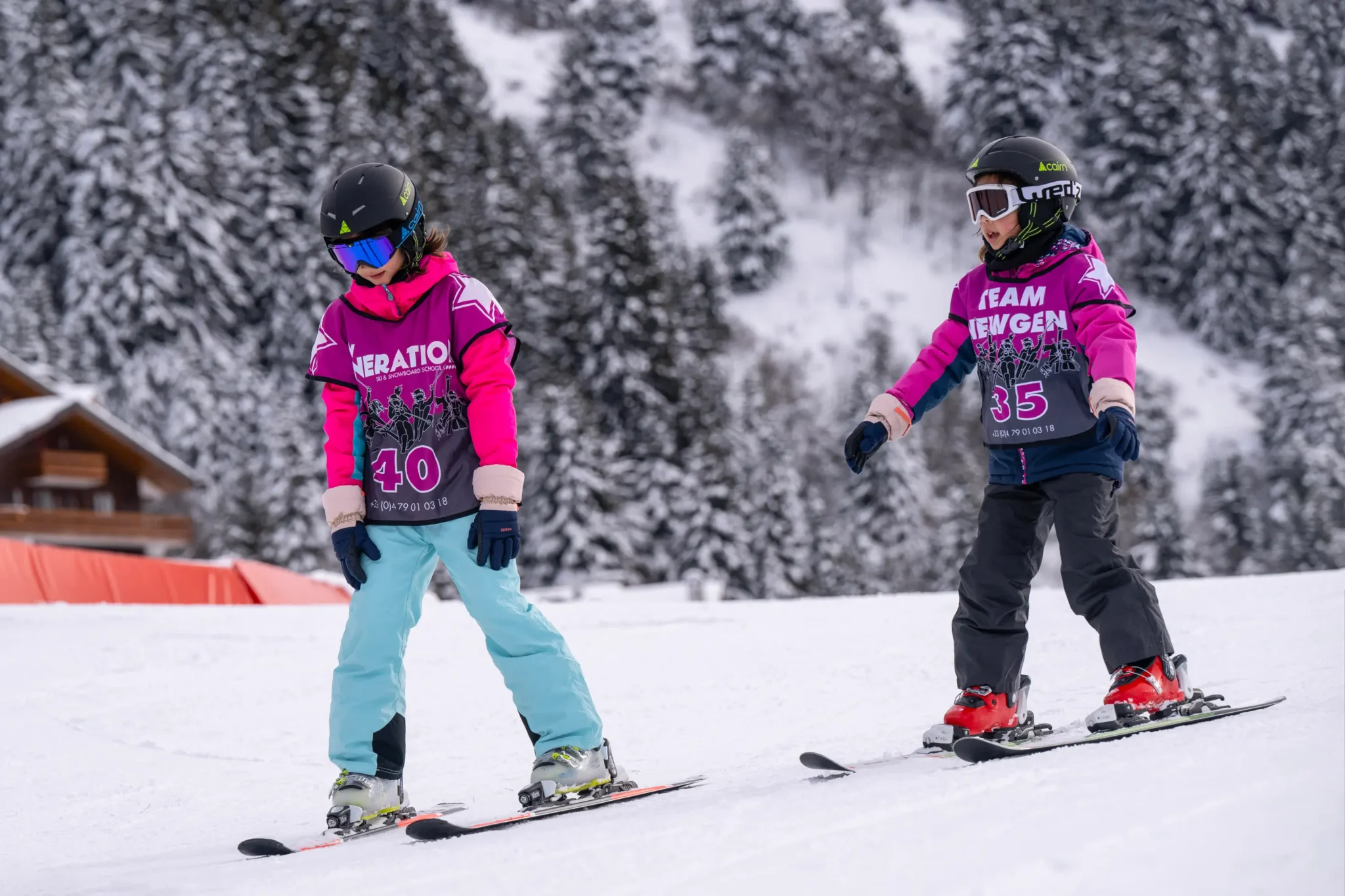 Two children skiing on snowy slope.