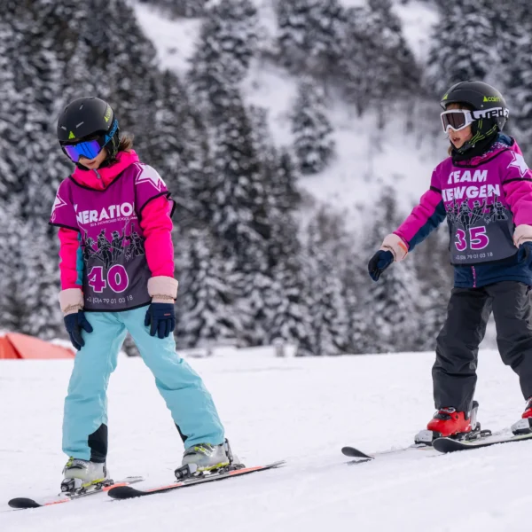 Two children skiing on snowy slope.