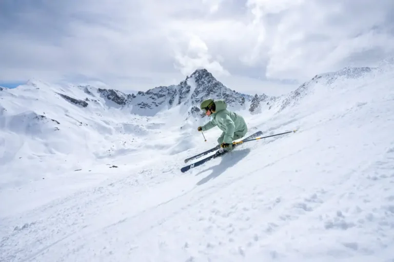 Skier carving fast turn down steep powder slope in the Alps