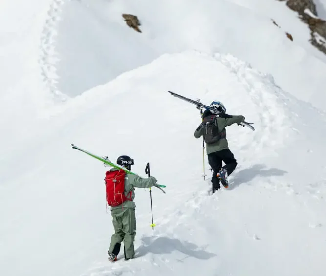 Skifahrer, die einen verschneiten Bergpfad hinaufsteigen. Experten-Off-Piste-Skikurse 