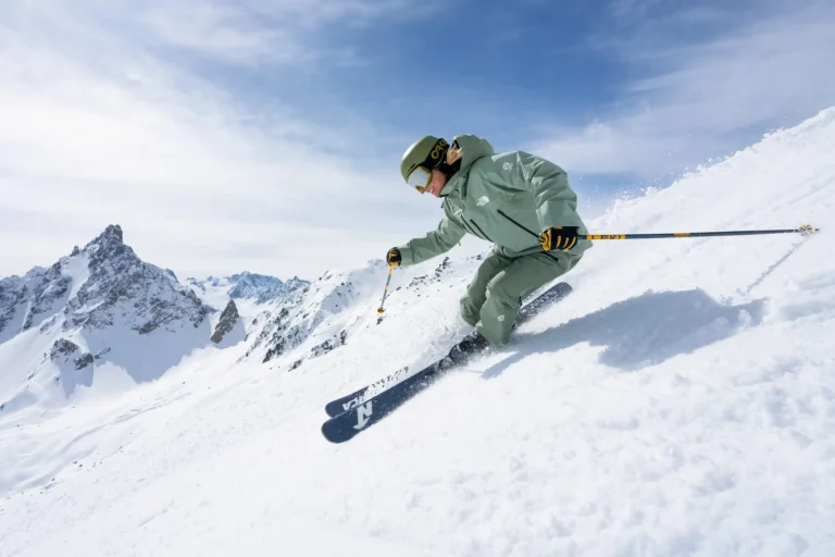 Skier carving a steep powder slope in the Alps under blue sky