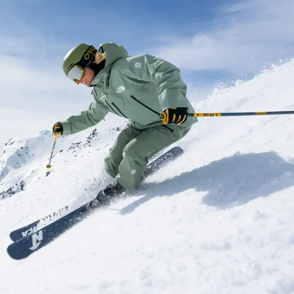 Skier carving a steep powder slope in the Alps under blue sky