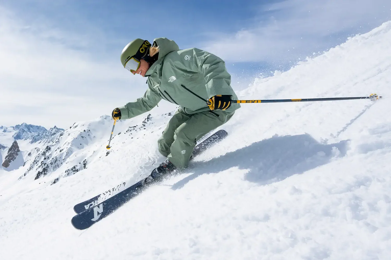 Skier carving a steep powder slope in the Alps under blue sky