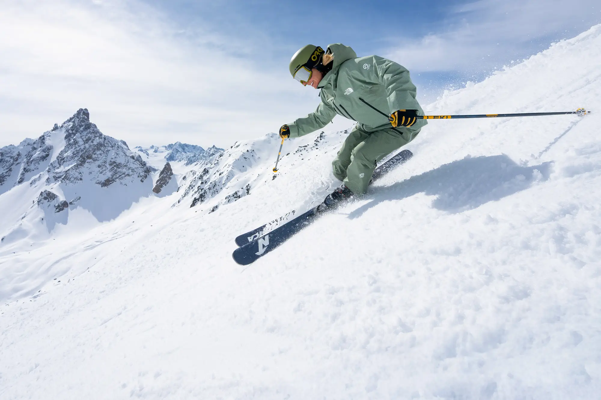 Skier carving a steep powder slope in the Alps under blue sky