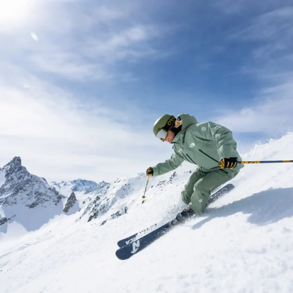 Skier carving a steep powder slope in the Alps under blue sky