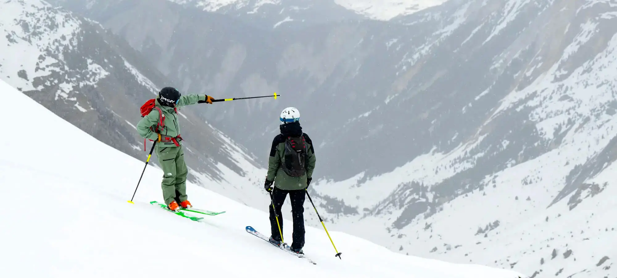 A New Generation ski instructor pointing out a route to a guest off-piste.