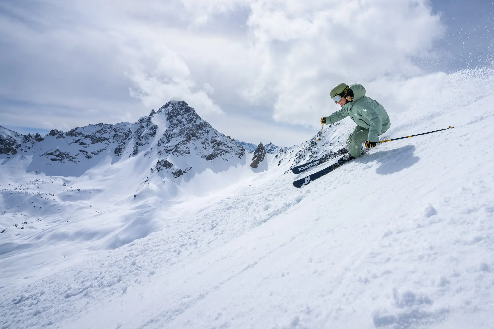 new generation ski and snowboard school skiing down the mountain wearing green uniform