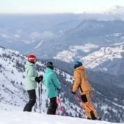 2 Skiers and a ski instructor, looking down the valley from the top of Meribel.