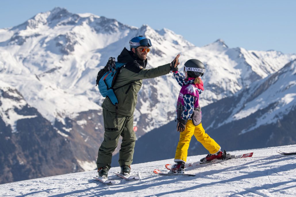 ski instructor and child high fiving