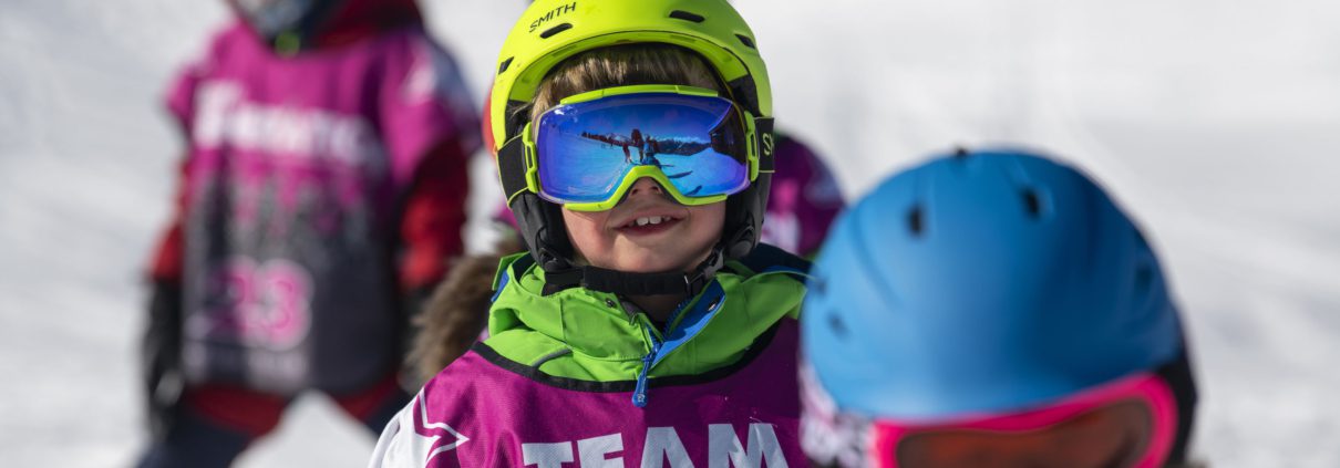 Smiling boy in ski school with green helmet