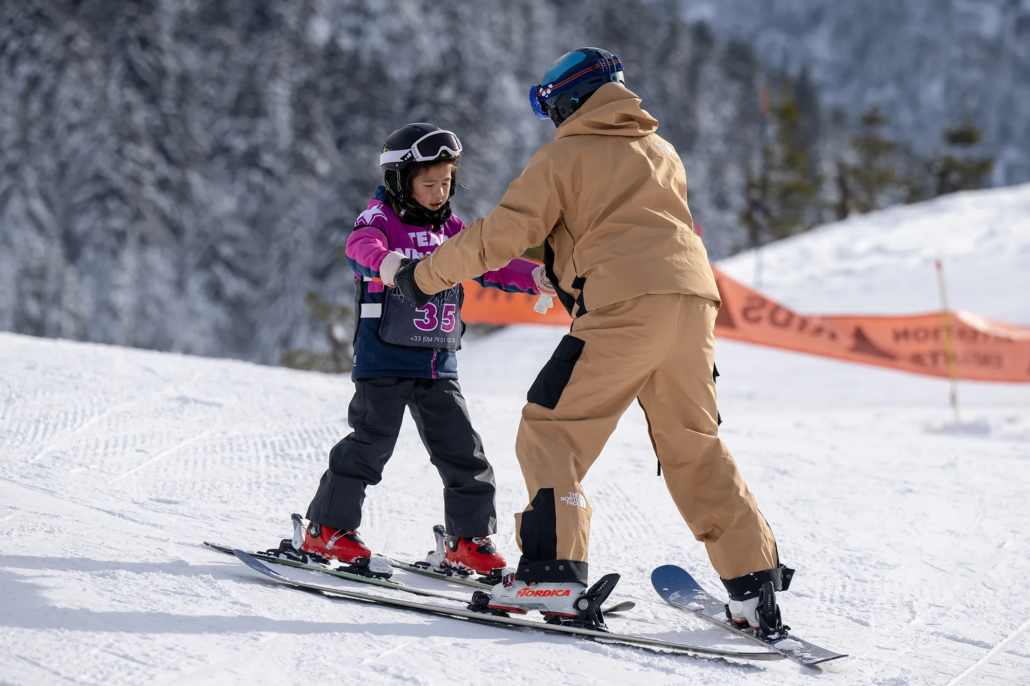 A child learning to ski being guided by a ski instructor