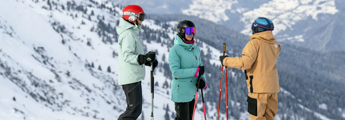 A Ski Instructor with 2 Students looking down a mountain valley