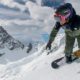 A snowboard instructor making a turn with an impressive mountain backdrop